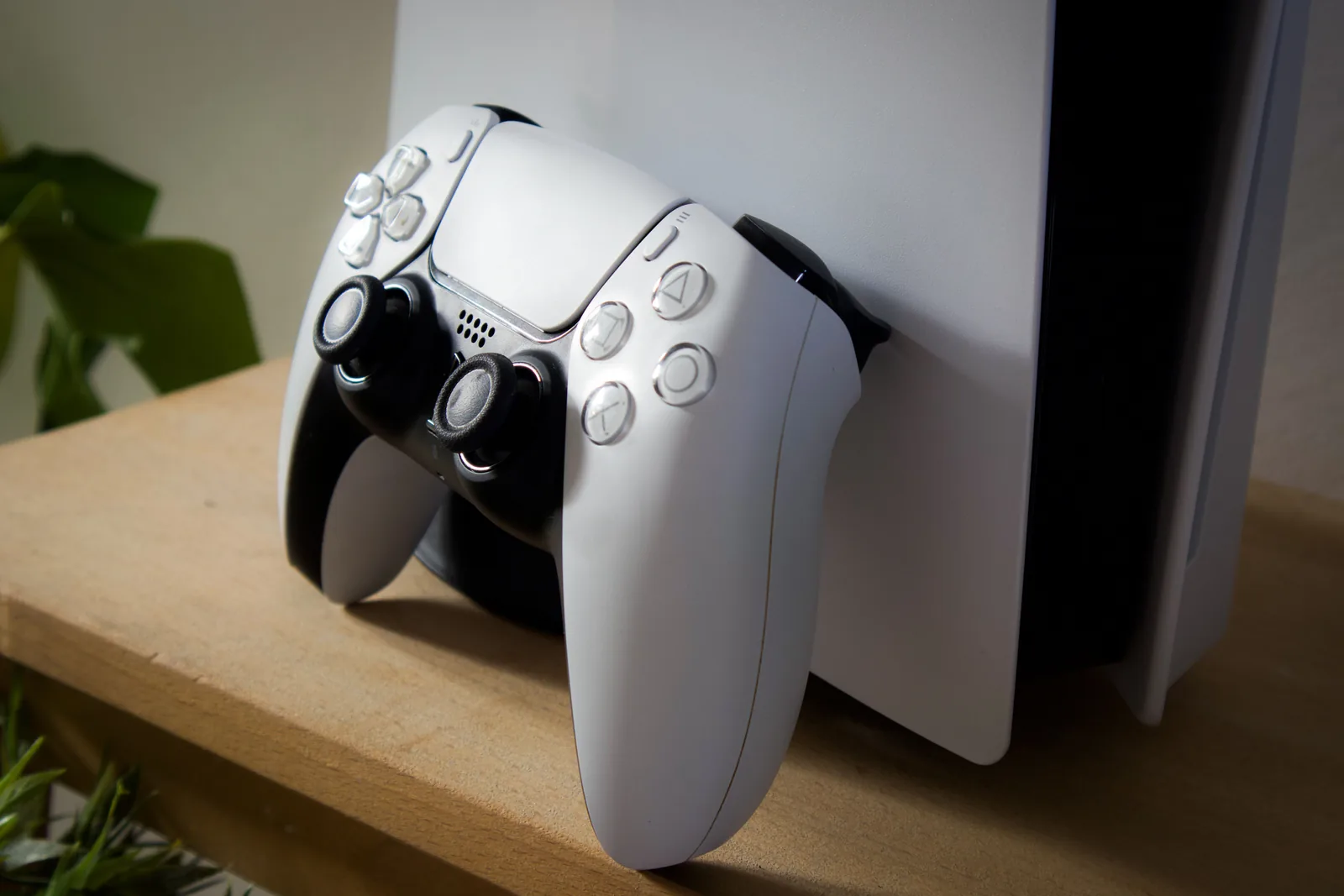 Κονσόλα PlayStation 5 και χειριστήριο DualSense σε ξύλινο ράφι
